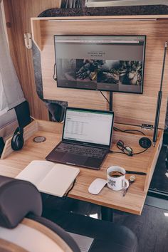 a laptop computer sitting on top of a wooden desk next to a cup of coffee