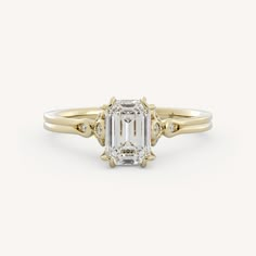 an emerald cut diamond engagement ring with three stone accents on the shoulders and side stones in yellow gold