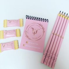 four pink pencils with writing on them next to a spiral notebook and five erasers