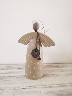 a small angel figurine sitting on top of a wooden table next to a white wall