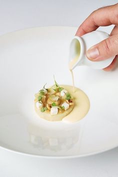 a person pouring sauce onto a plate with food on it