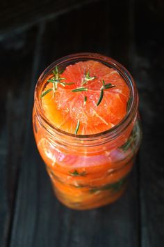 a glass jar filled with orange slices on top of a wooden table