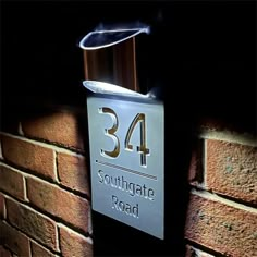 an illuminated sign on the side of a brick wall reads,'34 southgate road '