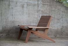 a wooden chair sitting in front of a concrete wall