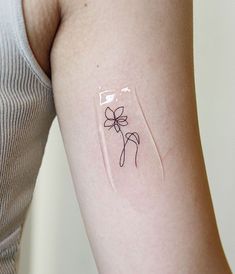 a woman's arm with a small flower tattoo on the left side of her arm