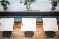 three tables and two chairs with plants in the window sill behind them on a wooden floor