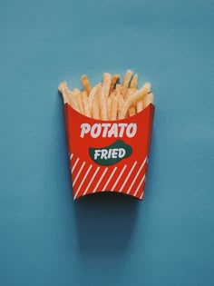 a red box filled with french fries on top of a blue surface