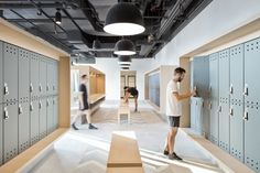 a man standing in the middle of lockers and looking at something on the wall