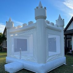 an inflatable castle sits on the grass near a house with white walls and windows