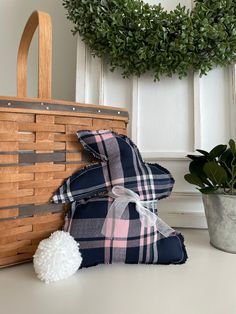 a basket and some pillows sitting on a table next to a potted plant with a wreath in the background