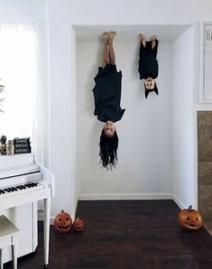 two people upside down on their heads in the middle of a room with pumpkins