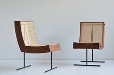 two chairs sitting next to each other on top of metal legs and wooden backrests