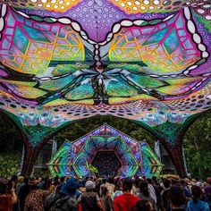 a large group of people standing under a colorful structure