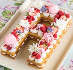 a letter shaped cake with strawberries and other toppings on a white platter