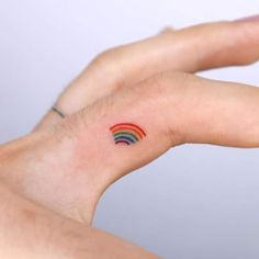 a person's hand with a small rainbow tattoo on it