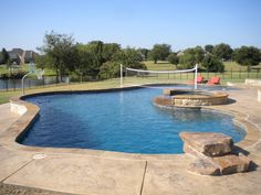 a pool with a volley ball net in the middle and some rocks on the side