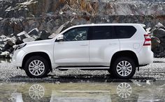 a white suv is parked in front of some rocks