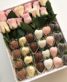 a box filled with lots of different types of chocolates next to flowers and leaves