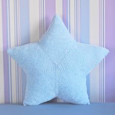 a blue star shaped pillow sitting on top of a bed next to a striped wall