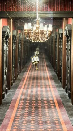 a long hallway with chandelier hanging from it's ceiling and lights on either side