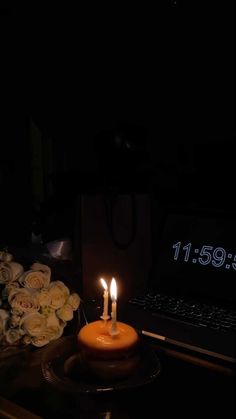 a lit candle sitting on top of a table next to flowers and a laptop computer