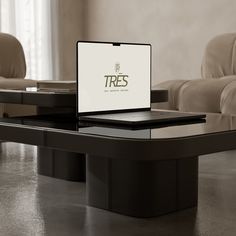 an open laptop computer sitting on top of a black table in front of a couch