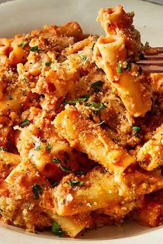 a white plate topped with pasta covered in sauce and parmesan cheese next to a fork