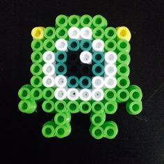 a green and white beaded object sitting on top of a black table next to a pair of scissors