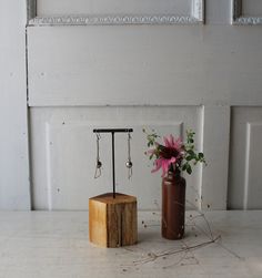 a vase filled with flowers next to a pair of earrings on a wooden block in front of a door