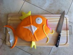 a cake shaped like a fish sitting on top of a cutting board next to a knife