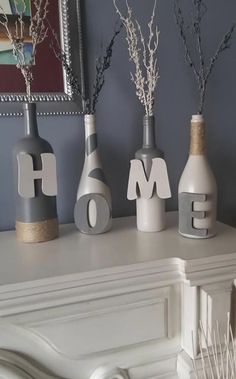 three vases with the word home spelled out in front of them on a mantle