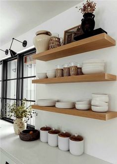 the shelves in the kitchen are filled with plates, bowls and vases on them