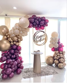 balloons are arranged in the shape of an arch for a happy birthday party with gold, purple and white balloons