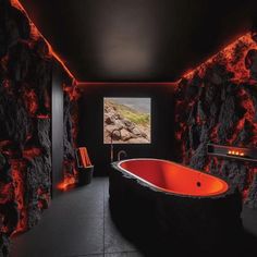 a black and red bathroom with an orange bathtub in the middle, rocks around it