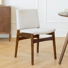 a white chair sitting next to a wooden table on top of a hard wood floor