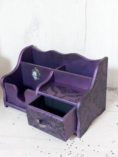 a purple desk set with two drawers and a clock on it's side, sitting on a white surface