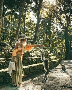 a woman standing in the middle of a forest with two monkeys on either side of her