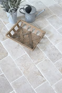 a potted plant sitting on top of a white tile floor next to a watering can