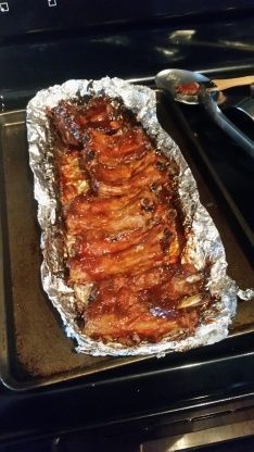 the meat is being cooked in the oven with tongs next to it and on top of the grill