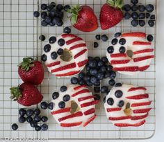 red, white and blue desserts are arranged on a cooling rack with strawberries