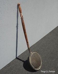 a wooden stick sticking out of the side of a wall next to a metal pan