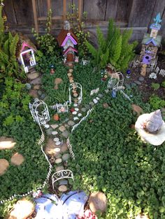 an aerial view of a garden with miniature houses in the center and small trees on either side