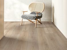 a chair sitting on top of a wooden floor next to a white wall and window