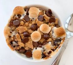 a bowl filled with dessert sitting on top of a table next to a silver spoon