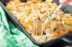 a person scooping some food out of a casserole dish with cheese and parmesan