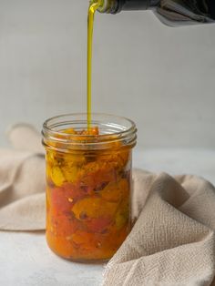 a jar filled with food sitting on top of a cloth covered table next to a bottle