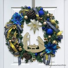 a christmas wreath with the nativity scene hanging from it's center and decorations around it