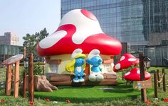 an inflatable mushroom house with two smurfs standing next to each other