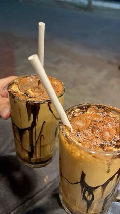 two glasses filled with iced coffee sitting on top of a table next to each other