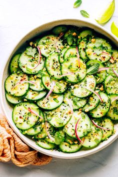 a bowl filled with cucumbers and onions on top of a white tablecloth